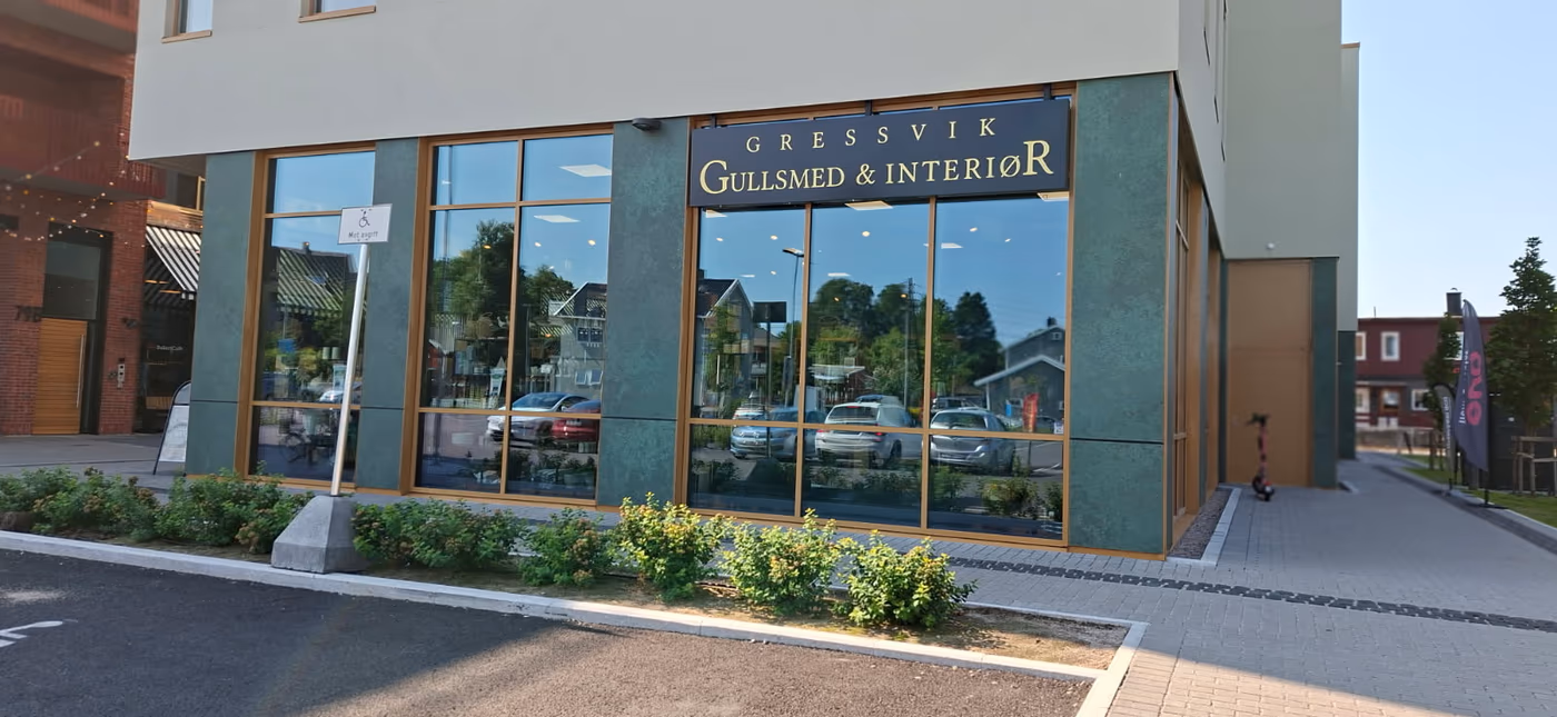 Gullskriften «Gressvik Gullsmed & Interiør» på butikkvinduet, med kafébord utenfor