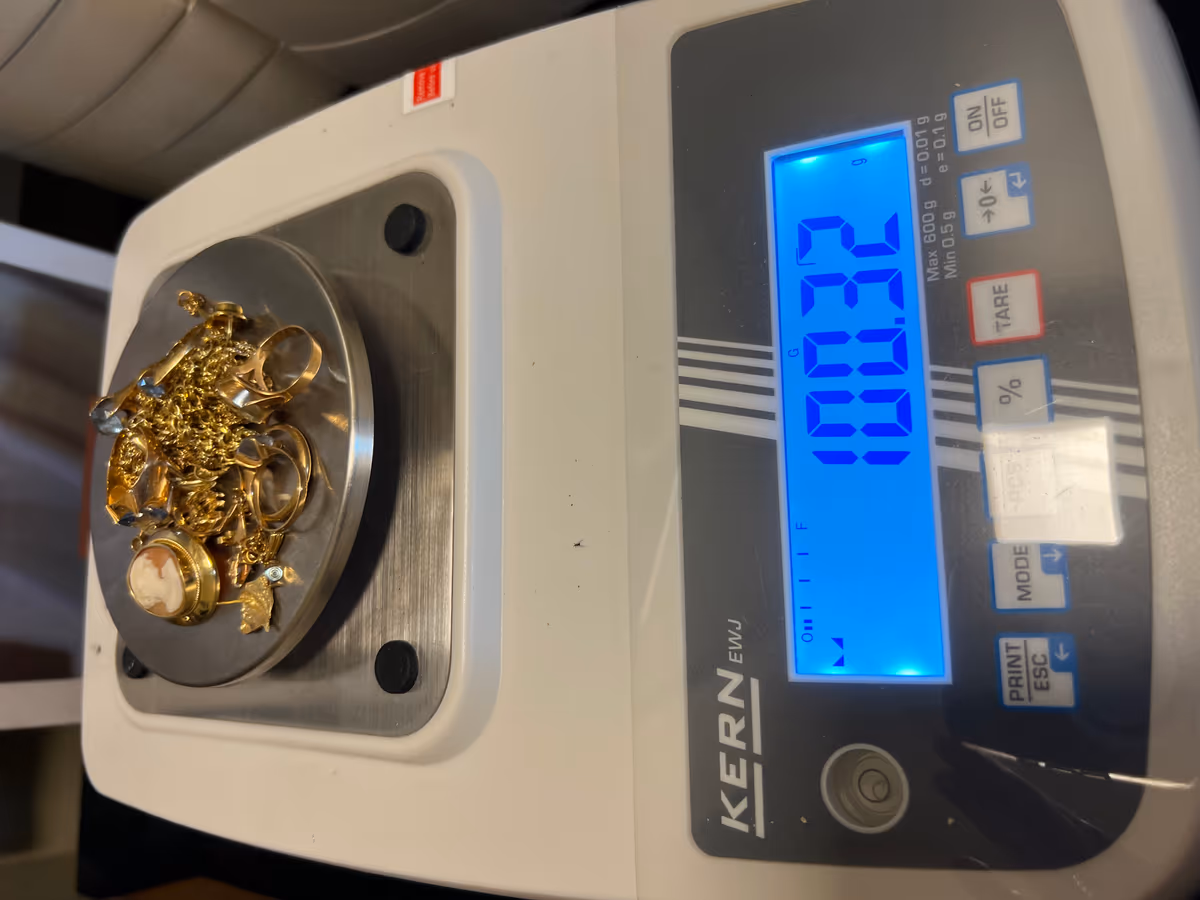 Gull på presisjonsvekt som viser vekten 100,32 gram