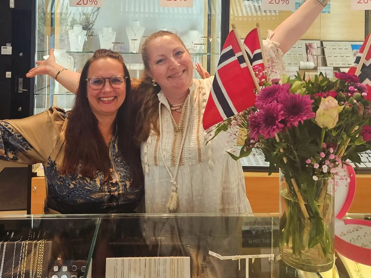 To av damene bak disken med armene ut, og norske flagg i blomstervasen foran