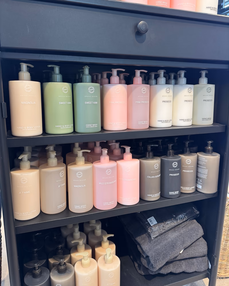 Svart skap fylt med håndsåpe og lotion fra Bruka Design i pastellfarger, med duftene Magnolia, Sweet Kiwi, Pink Prosecco, Prosecco, Je t'aime, Wild Strawberry og Italian Bergamot, hos Gressvik Gullsmed