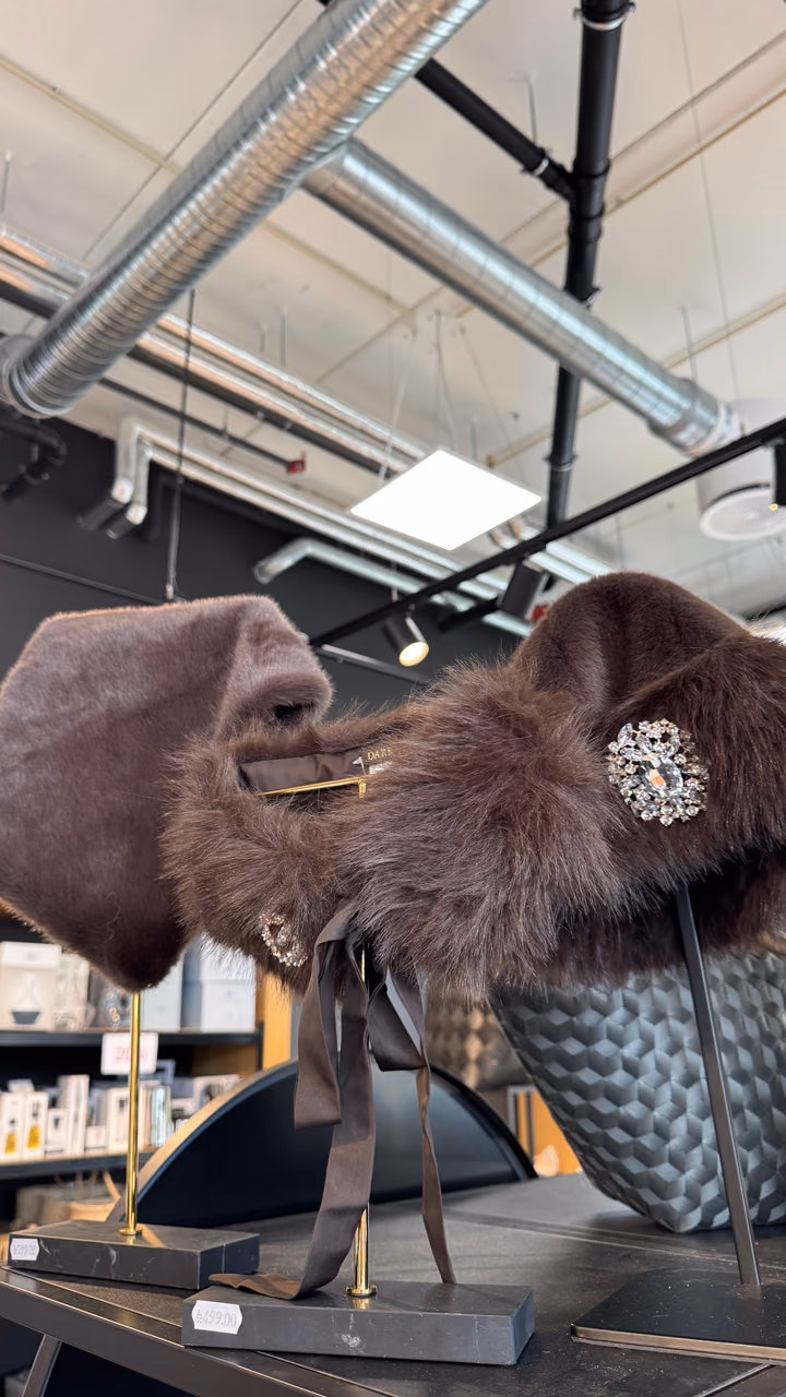 Mørkebrun halskrage i fuskepels med strass-brosje fra Dark Department, på stativ i butikken