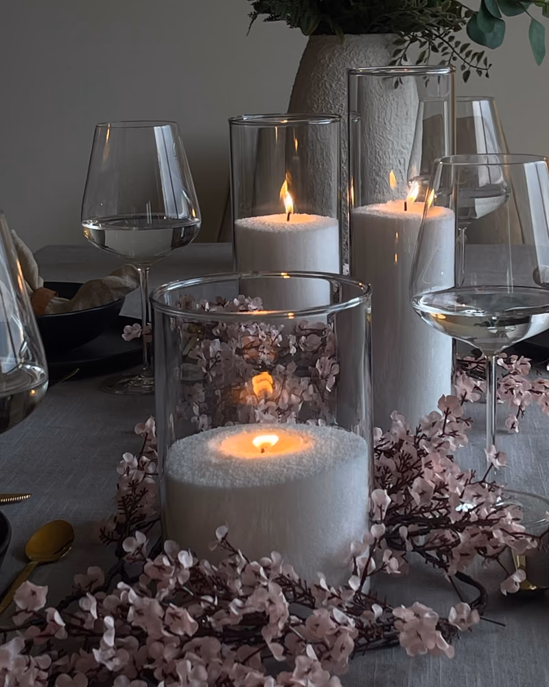 Tente lys av Illumina lyssand i glass på et dekket bord med tørkede blomster rundt