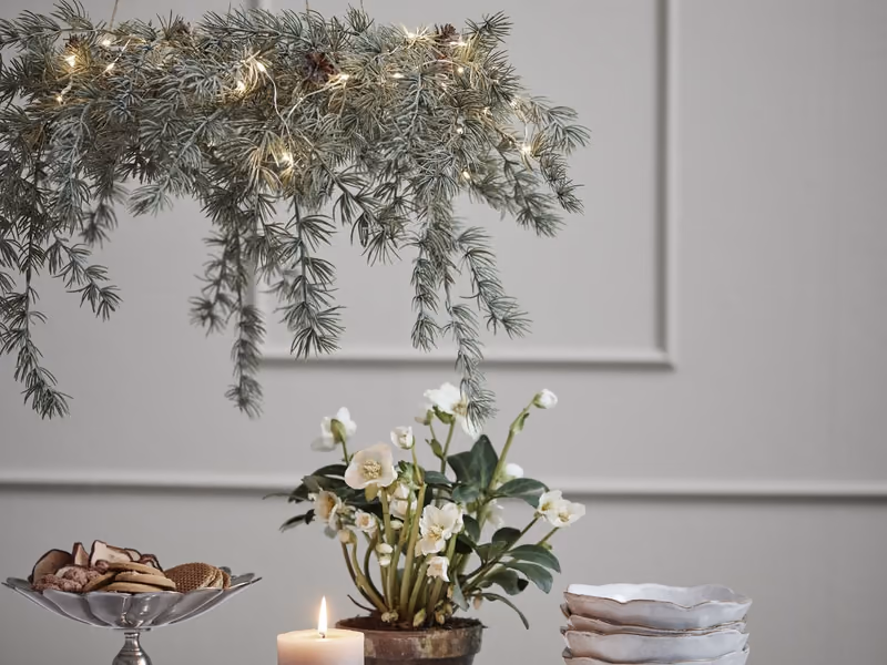Julebord fra Lene Bjerre med granbarkrans, tent lys og stablet servise