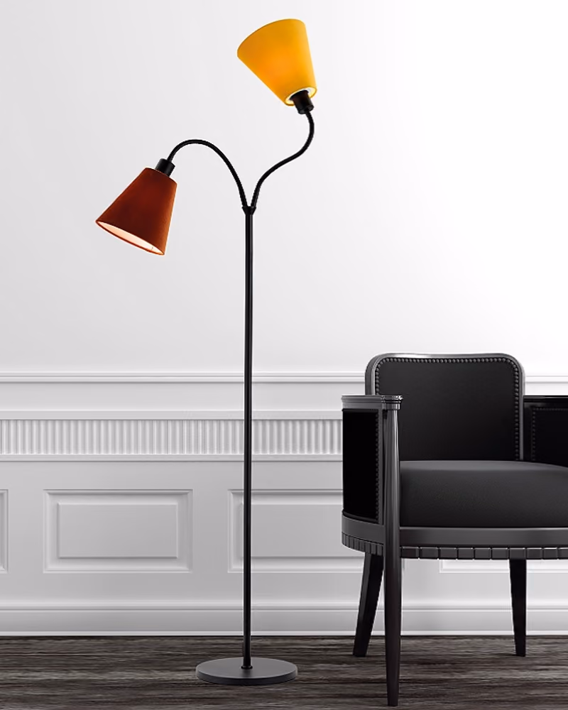 Sort gulvlampe fra MS Belysning med to skjermer i gult og rødt, ved siden av en lenestol